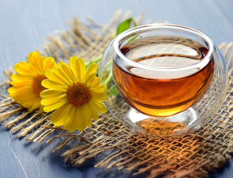 Tasse Tee auf Textil mit zwei gelben Blumen